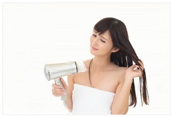 ドライヤーで髪を乾かす女性